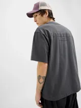 Camiseta gris oscuro de manga corta y cuello redondo con calce holgado y estampa pequeña en el pecho. Confeccionada en jersey simple peinado.