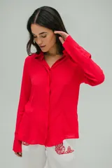 Camisa roja de crepé fluida con cuello camisero, mangas largas con puños abotonados y cierre frontal con botones.