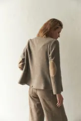 Chaqueta corta con cuello solapa, manga larga con coderas aplicadas, cierre frontal con botones y bolsillos ojal. Con forro.