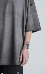 Remera de manga corta, calce extra oversize, color gris oscuro con efecto gastado/degradado. Presenta roturas y detalles deshilachados en cuello, hombros y puños.