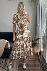 Vestido midi con estampado floral en tonos marrones y beige, corte camisero con cuello en V y botones frontales.