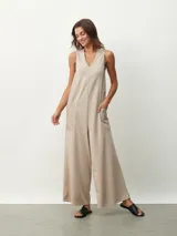 Mono largo color beige, de corte holgado, con cuello redondo y mangas cortas. Presenta bolsillos laterales y detalle de costuras verticales en el frente.