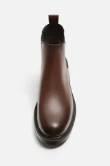 Bota Chelsea marrón de cuero, con elásticos laterales y tirador trasero. Suela negra con ligero tacón.