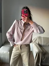 Camisa a rayas verticales rojas y blancas con cuello con solapa marrón y lazo al cuello.