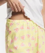 Pijama corto de algodón con blusa blanca de cuello V con botones y mangas cortas onduladas, y short amarillo con estampado de corazones y cintura elástica.