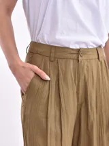 Pantalón de vestir color oliva, de corte amplio y tiro alto, con pinzas en la cintura y textura arrugada.