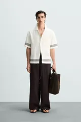 Pantalón marrón oscuro de corte amplio, confeccionado en mezcla de algodón y lino. Presenta cintura elástica, bolsillos laterales y trasero de parche, pliegues frontales, cierre con cremallera y botón.