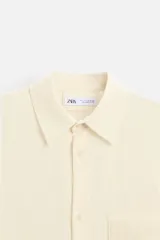 Camisa color crema de corte relaxed fit, confeccionada en tejido con mezcla de viscosa. Tiene cuello solapa, manga larga con puños abotonados, bolsillo de parche en el pecho y cierre frontal con botones.