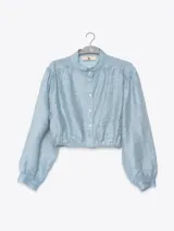 Camisa celeste de tela arrugada, con cuello mao, mangas largas abullonadas y puños elásticos.