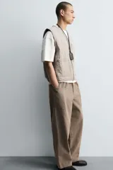 Pantalón cargo de algodón color marrón con efecto lavado, corte relajado y tiro medio. Presenta cintura elástica con botón y cierre de cremallera, bolsillos delanteros, bolsillos plastrón en la espalda y grandes bolsillos cargo en las perneras.