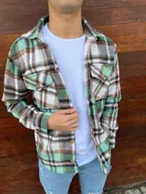 Sobrecamisa de paño a cuadros en tonos verde, marrón y blanco, con cuello clásico, cierre frontal con botones, dos bolsillos con solapa en el pecho y corte recto.