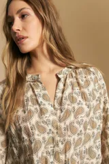 Camisa de manga larga con cuello mao y estampado paisley en tonos beige, marrón y azul sobre fondo claro. Presenta un calce holgado y puños ajustados.