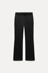 Pantalón negro de tiro medio con cintura con trabillas y corte flare. Cierre frontal con cremallera, botón y gancho metálico.