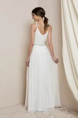 Vestido largo blanco con escote en V, breteles finos y falda plisada con abertura lateral. El corpiño está adornado con cuentas de cristal.