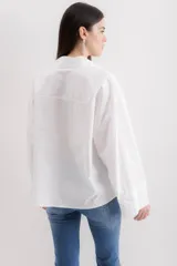 Camisa blanca de algodón con cuello clásico, mangas largas con puños abotonados y bolsillo de parche en el frente.