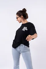 Remera negra de corte oversize con estampado frontal que dice "MIJA DREAM BIG" en tipografía blanca y rosa.