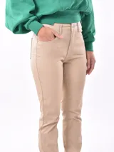 Pantalón de vestir color beige, de corte recto, con bolsillos laterales y traseros. Se ajusta a la cintura con cinturón de cuero marrón.