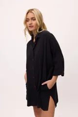 Vestido camisero a rayas verticales de colores pastel, con cuello camisero, cierre frontal con botones y mangas largas.