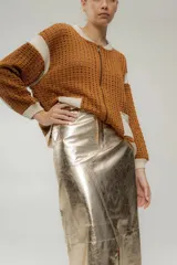 Falda midi de cuero sintético color champagne, con corte recto y detalle de costuras diagonales.