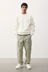 Pantalón cargo color verde claro, de corte relajado, con bolsillos laterales con solapa y botón a presión. Confeccionado en popelina de algodón con elástico en la parte posterior de la pretina y cierre con botón a presión.