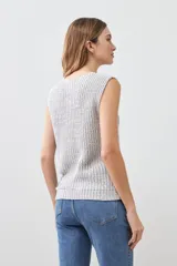 Chaleco tejido gris con botones de madera, sin mangas y cuello redondo.