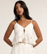 Blusa cropped blanca de algodón con bordado floral, breteles finos y escote en V con lazo frontal.