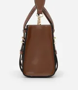 Bolso satchel mediano color marrón, confeccionado en poliuretano, con correa de mano con detalles de hebilla y costura, asa larga desmontable con gorgorão y cierre por cremallera.