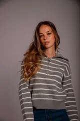 Sweater de punto color crema con rayas horizontales negras, cuello polo con cierre metálico dorado y mangas largas.