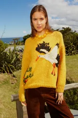 Sweater tejido de lana color amarillo con bordado de cigüeña en el frente y detalle floral en la manga.