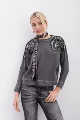 Buzo gris de algodón rústico con mangas dolman y cuello redondo. Apliques bordados con mostacillas y lentejuelas en los hombros.