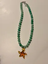 Collar de piedras naturales en tonos verdes, con un dije de estrella de mar en color ámbar con detalles verdes.