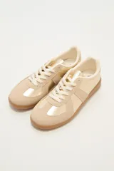 Zapatillas deportivas color beige y dorado con suela marrón.