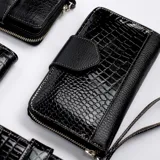 Billetera dorada con cierre metálico y solapa con el logo de la marca Vanitas. Tiene múltiples compartimentos para tarjetas y billetes. Incluye correa de muñeca extraíble.