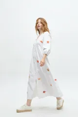 Vestido midi color arena con escote en V, mangas 3/4 abullonadas y cierre frontal con botones. Presenta bordados de motivos marinos.