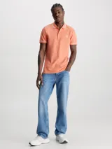 Chomba color salmón de corte slim fit, con cuello clásico y tapeta de dos botones. Presenta ribetes blancos en cuello y mangas, y logo CK bordado en blanco en el pecho.