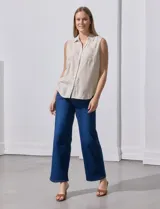 Camisa sin mangas de lino a rayas verticales azules y blancas, con cuello con solapa, escote en V, abertura central con botones y bolsillo en el pecho.