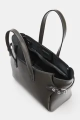 Bolso mini shopper de cuero sintético color gris oscuro, con doble asa de mano y detalles de ojales metálicos en los laterales. Incluye asa extraíble para llevar como bandolera y cierre magnético.