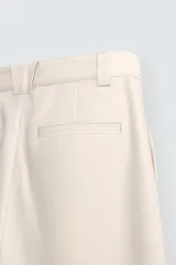 Pantalón negro de corte recto, con bolsillos frontales tipo parche y bolsillos traseros de ojal.