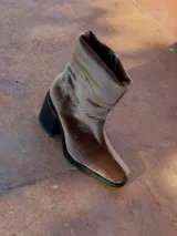 Bota de caña baja color marrón de terciopelo con efecto abullonado y cadena desmontable con el logo de la marca.