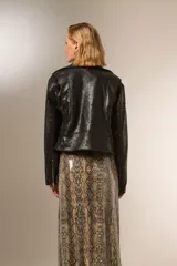 Chaqueta negra de eco-cuero con cuello solapa, cierre frontal asimétrico y cinturón ajustable. Incluye bolsillos laterales con cierre y detalles de tachas plateadas en cuello y solapa.