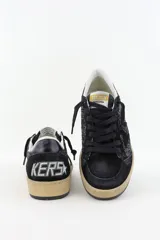 Championes de caña baja Golden Goose modelo Ballstar, color negro con acabado brillante o glitter en los laterales y gamuza en puntera y cordones. Presentan efecto desgastado en la suela de goma color beige.