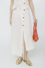 Falda midi color crudo con botones frontales con forma de tomate y tajo frontal.