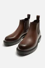 Bota Chelsea de cuero color marrón con elástico lateral y tirador trasero. Suela track de goma negra.