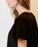 Remera de jersey flama 100% algodón, color negro, de línea A y fit relajado, con escote redondo, manga corta y recortes a los costados.