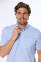 Camisa celeste con estampado de cuadros blancos, de manga corta, con cuello abotonado y bolsillo en el pecho.