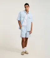 Bermuda regular de jeans celeste con cintura elástica, cordón ajustable y estampado de rayas finas.