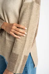 Sweater de punto color beige con mangas largas combinadas en tonos de marrón.
