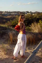 Pantalón blanco de lino 100% natural, con cordones regulables en los tobillos y detalles estampados en los costados.