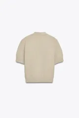 Chaqueta amarilla de punto con escote de pico y manga corta. Cierre frontal con botones en forma de estrella.