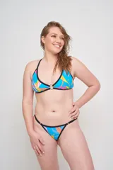 Corpiño de bikini triangular con estampado abstracto en tonos rosados y verdes, con aro metálico en el centro y breteles finos negros.